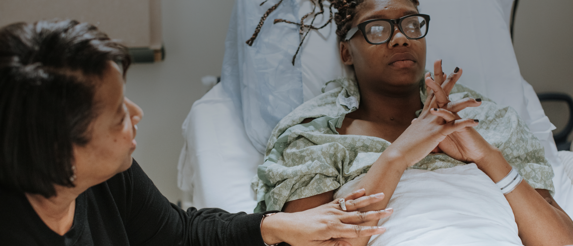 A woman touching the arm of a woman in a bed