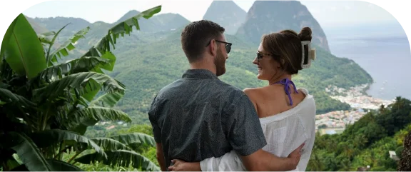 a man and woman sitting on a hill overlooking a body of water