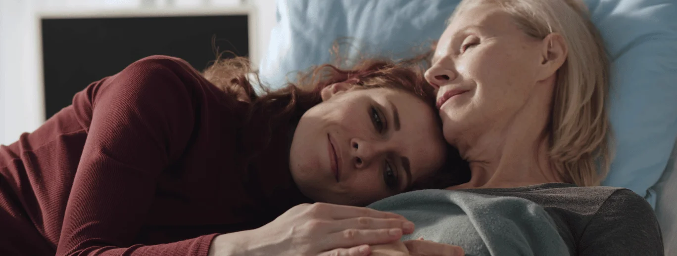 a woman lying on a bed with another woman smiling