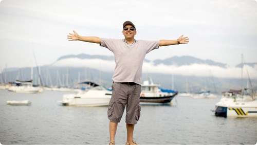A person standing on a dock with his arms spread out.